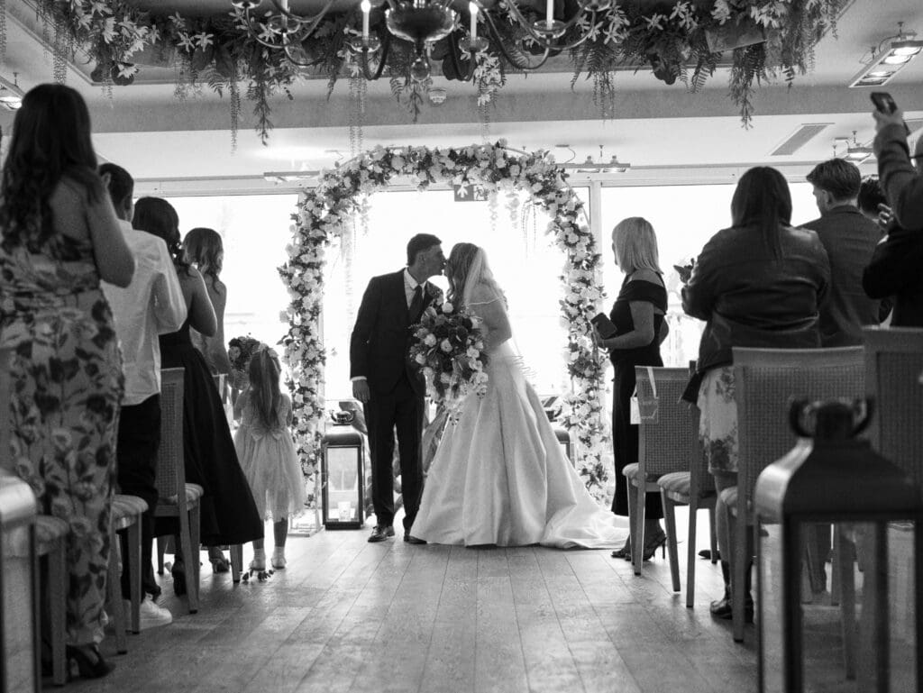 Floor-to-ceiling windows at the Roslin Hotel wedding ceremony in Southend, with natural beach light and candlelit décor.